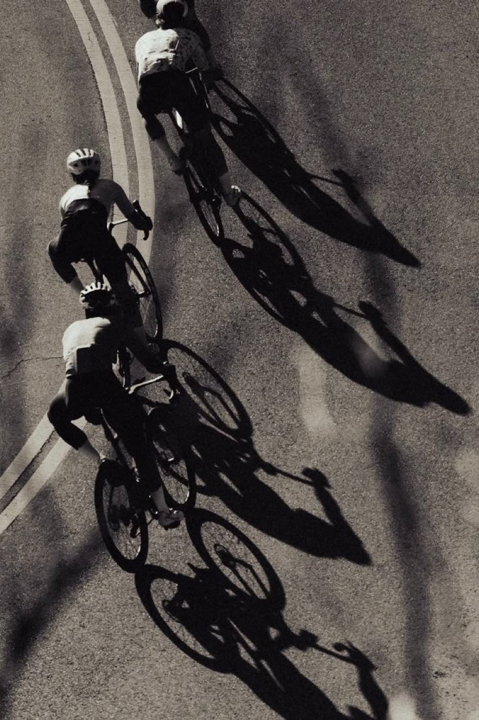 Three riders casting long shadows on the road